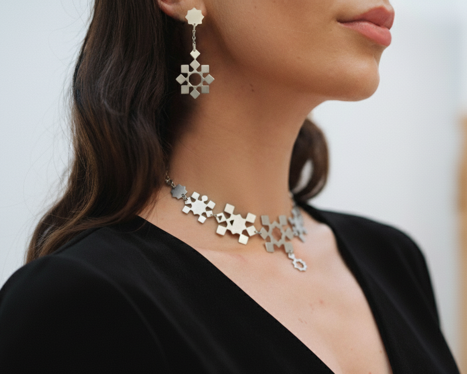 Close-up of a woman wearing a silver floral necklace and earrings against a neutral background